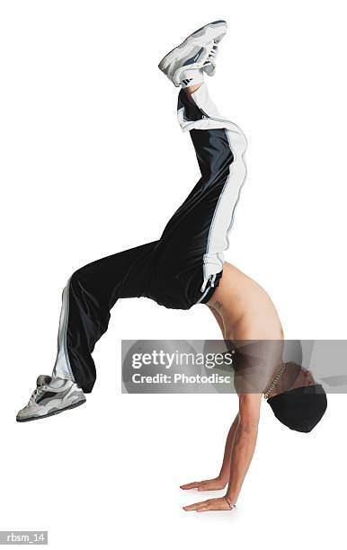 a young caucasian male breakdancer in black pants and no shirt and a knit cap is flipped upside down balancing on his hands with his legs in the air - pants down bildbanksfoton och bilder