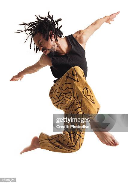 a young african american male modern dancer in yellow pants and a black tank top leaps into the air and spreads his arms apart - barefoot black men stock pictures, royalty-free photos & images