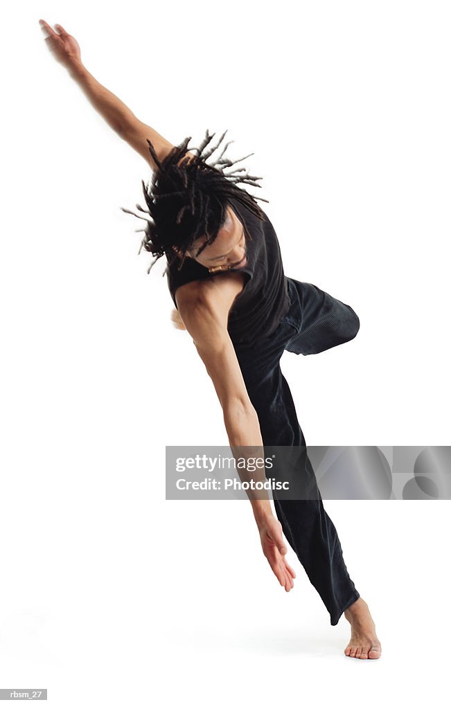 A young african american male modern dancer in black pants and a black tank top jumps up on one foot and spins