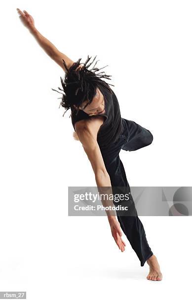 a young african american male modern dancer in black pants and a black tank top jumps up on one foot and spins - modern dancer stock pictures, royalty-free photos & images