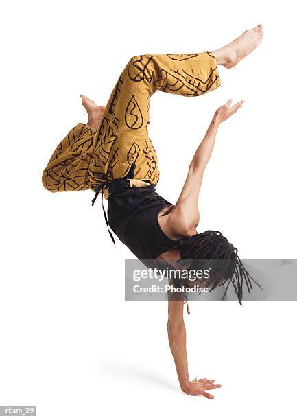 a young african american male modern dancer in yellow pants and a black tank top flips himself upside down with one arm and carefully balances - pants down bildbanksfoton och bilder