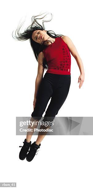 asian woman in black pants and red shirt jumping with legs together leaning to the side with hair flowing - roupa de discoteca imagens e fotografias de stock