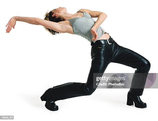 caucasian woman in black leather pants and grey tank top stepping forward and arching her back with her right arm reaching backward - roupa de discoteca imagens e fotografias de stock