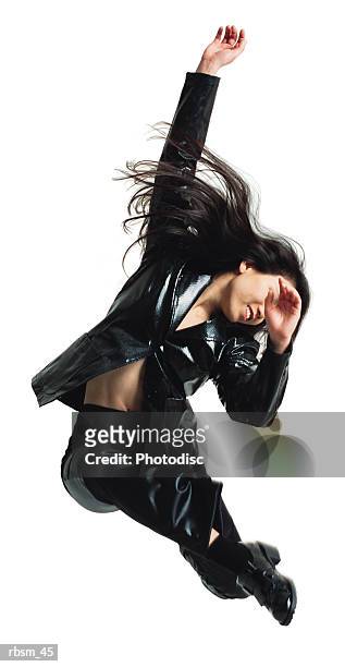 asain woman in black leather pants and jacket jumping with arms swinging in the air and legs swung forward - chaps stock pictures, royalty-free photos & images