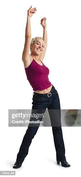 a young caucasian blonde female dancer in jeans and purple tank top shakes her hips as she lifts her arms up high above her head - roupa de discoteca imagens e fotografias de stock