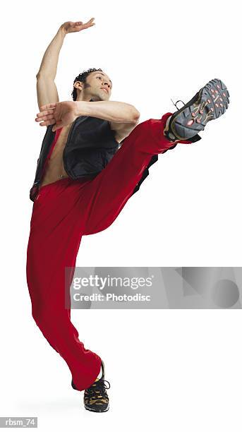 a young latin male modern dancer in red pants and a black vest and no shirt balances on one foot as he kicks his leg up and leans back - no stock pictures, royalty-free photos & images