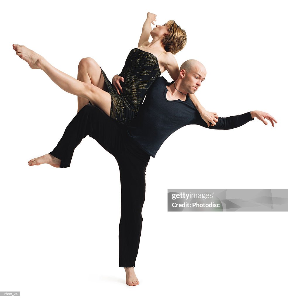 A young caucasian modern dance couple perform as the male balances on one leg as the female rests on his extended leg