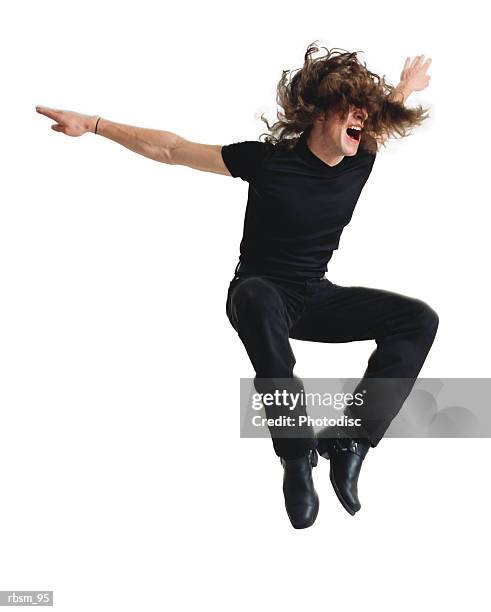 a young caucasian male modern dancer dressed in black with long hair jumps wildly into the air as he screams - mens long jump stockfoto's en -beelden