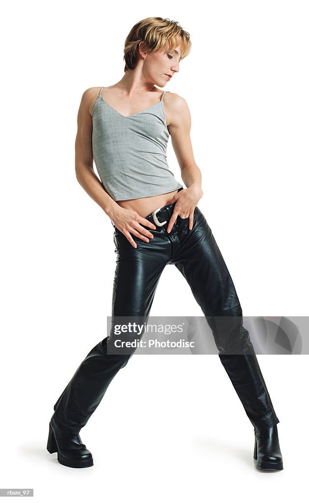 A young caucasian female dancer in black leather pants and a grey tank top swivels and shakes her hips from side to side