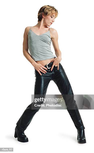 a young caucasian female dancer in black leather pants and a grey tank top swivels and shakes her hips from side to side - roupa de discoteca imagens e fotografias de stock