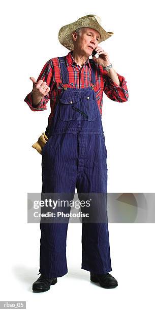 an elderly caucasian farmer chats on his cell phone - strohhut freisteller stock-fotos und bilder