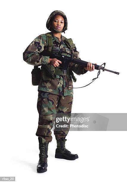 a young african american female soldier stand in fatighues with her gun - boots rifle helmet stock-fotos und bilder