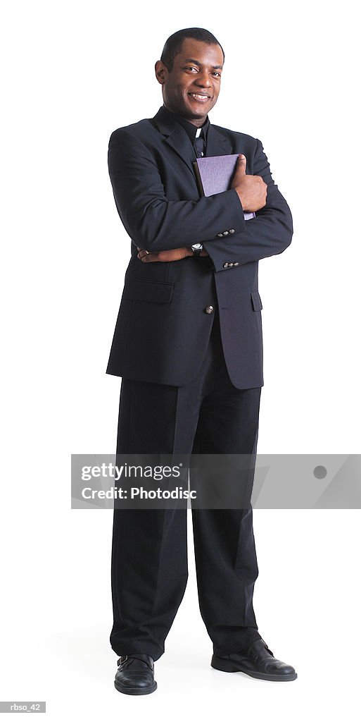 An african american male preacher holds a book and folds his arms