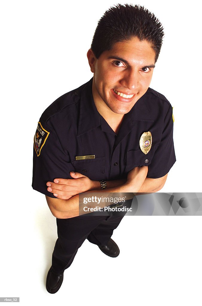 A hispanic male police officer in uniform smiles as he looks up at the camera