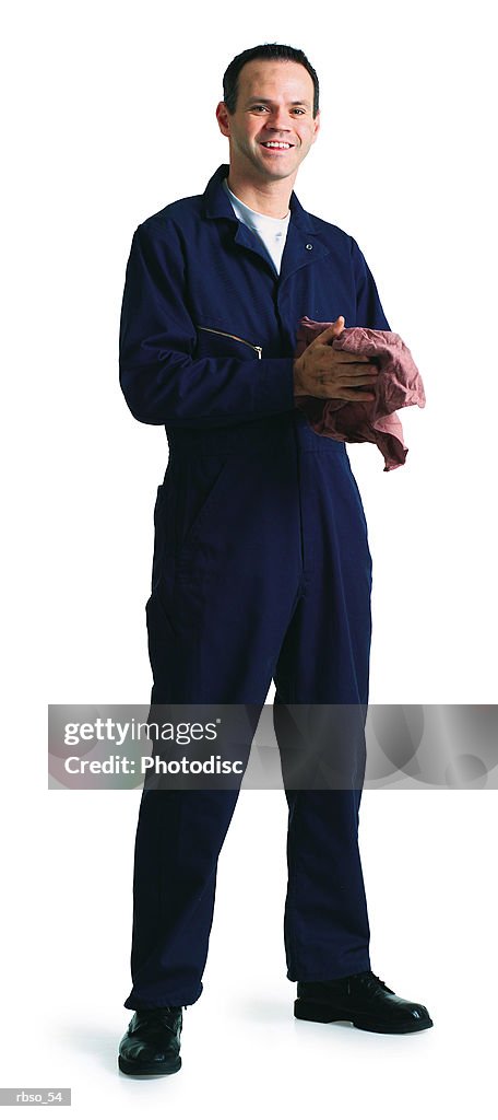 A caucasian male mechanic in a blue jumpsuit cleans his hands with an oily rag