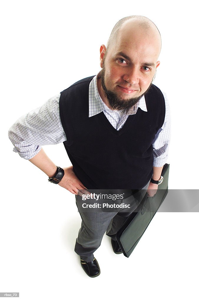 A bald caucasian male designer with a goatee holds his portfolio and smiles as he looks up at the camera