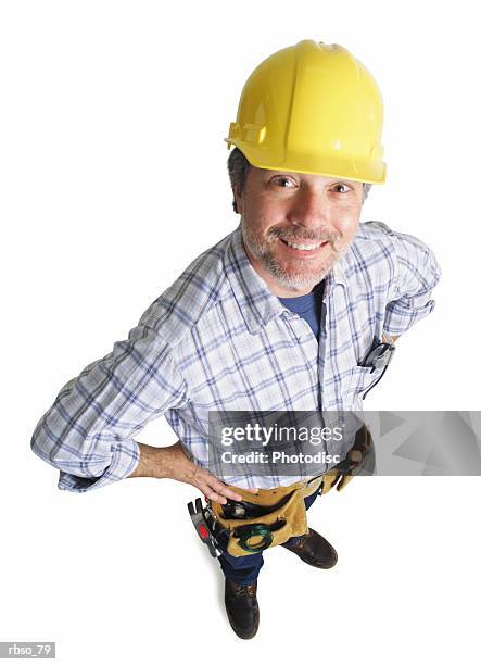 a caucasian male construction worker wearing a tool belt smiles as he looks up at the camera - belt stockfoto's en -beelden