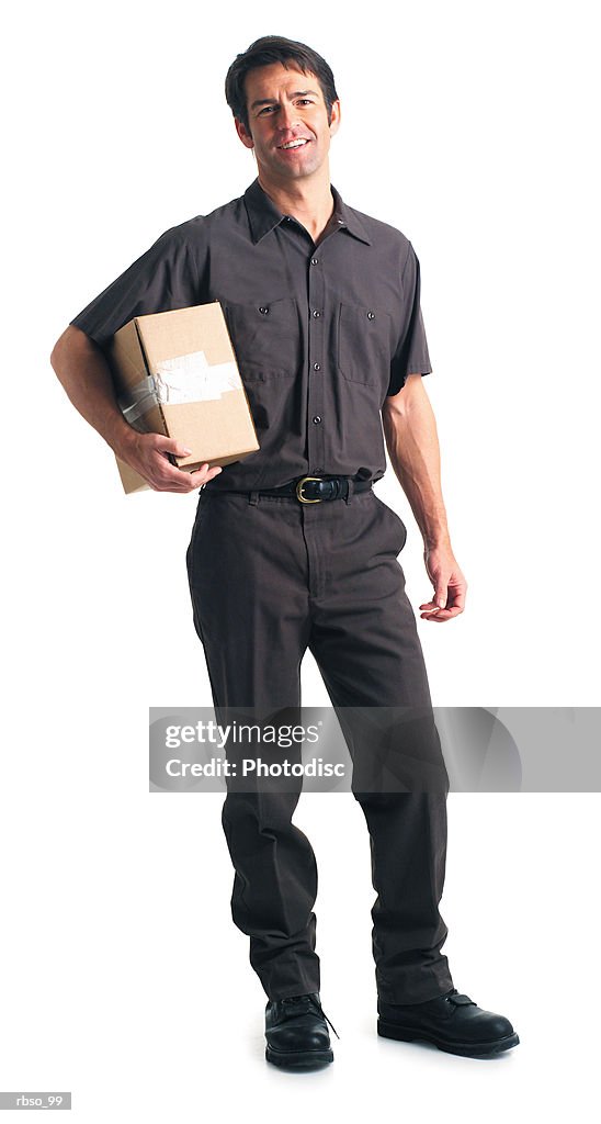 A caucasian male delivery man dressed in a brown uniform holds a package under one arm