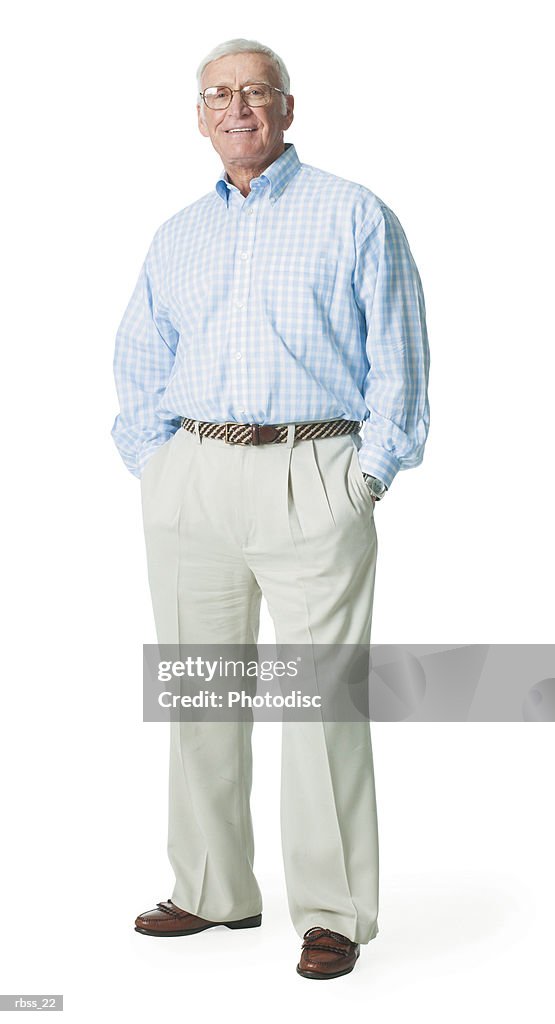 A man in a blue checkered shirt smiles with his hands in his pockets.