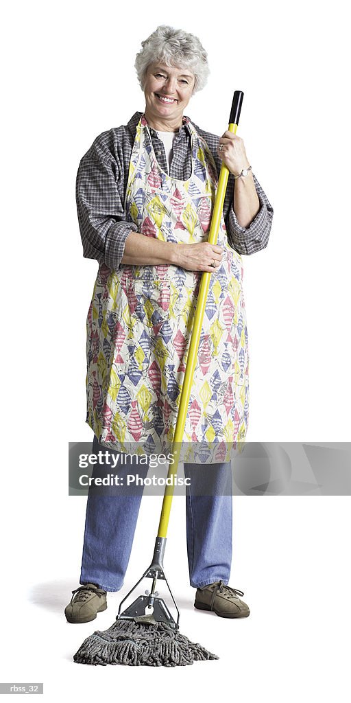 Happy elderly woman wearing an apron mops the floor.