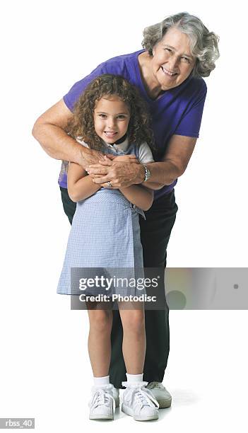 grandmother hugs her granddaughter while they smile at the camera. - smile stockfoto's en -beelden