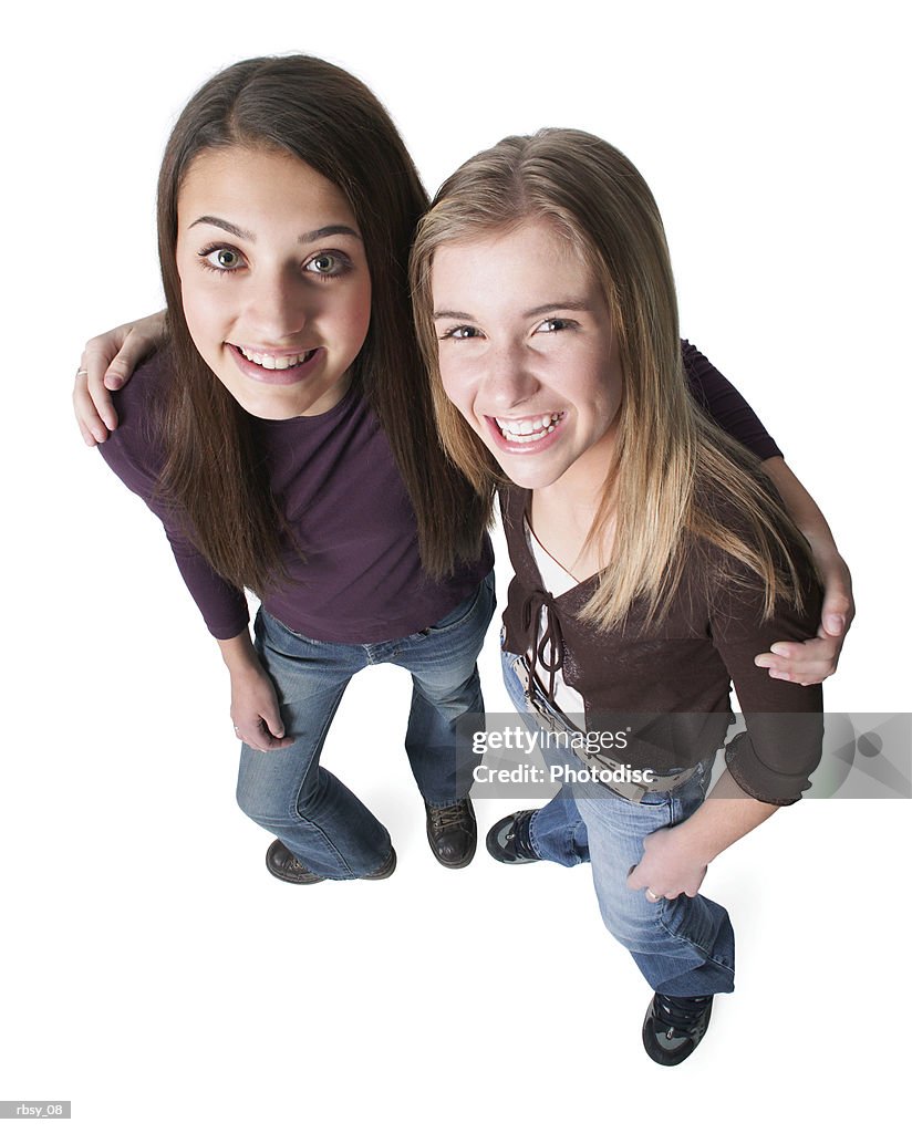 An ethnic female teen puts her arm around her caucasian blonde friend as they both look up to the camera and smile