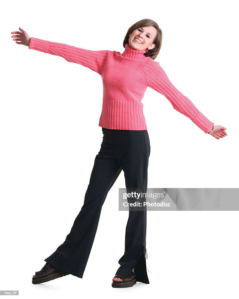 A caucasian teenage girl in black pants and a pink sweater stretches out her arms and smiles