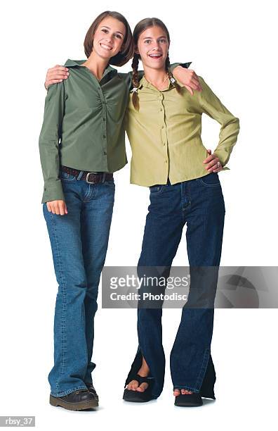two caucasian teenage girls in a jeans and green shirt puts their arms around each other and smile - smile stockfoto's en -beelden