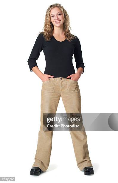 caucasian blonde female teen in tan pants and black shirt puts her hands in her pockets and smiles - tan tan stock pictures, royalty-free photos & images