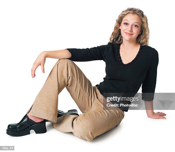a caucasian blonde female teen in tan pants and a black shirt as she sits down and smiles - pants down bildbanksfoton och bilder