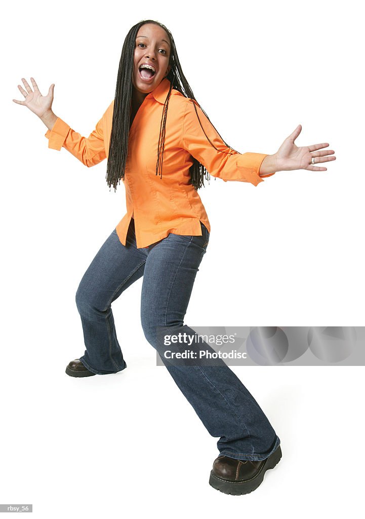 An african american teenage girl in jeans and an orange shirt spreads out her arms and smiles big