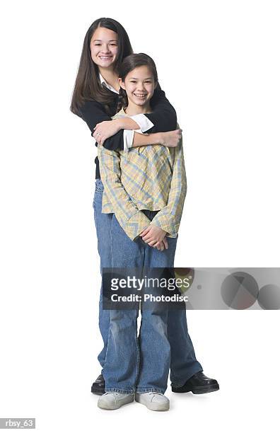 two young asian sisters put their arms around each other and smile at the camera - put together stock pictures, royalty-free photos & images