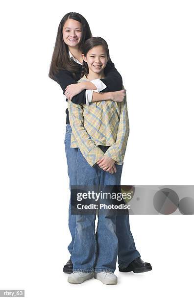 two young asian sisters put their arms around each other and smile at the camera - smile imagens e fotografias de stock