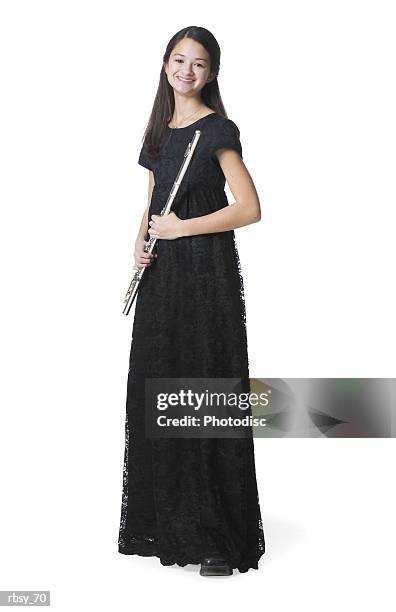 a young asian teenage girl in a black dress stands holding her flute and smiling - bläser stock-fotos und bilder