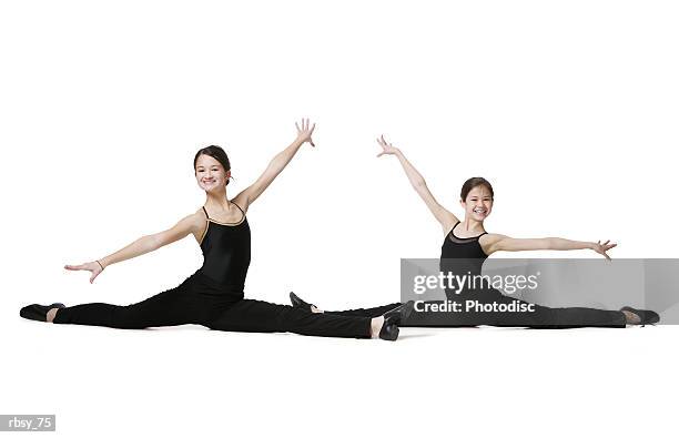 two young asian sisters dressed in black leotards stretch out in a dance pose and smile - smile imagens e fotografias de stock