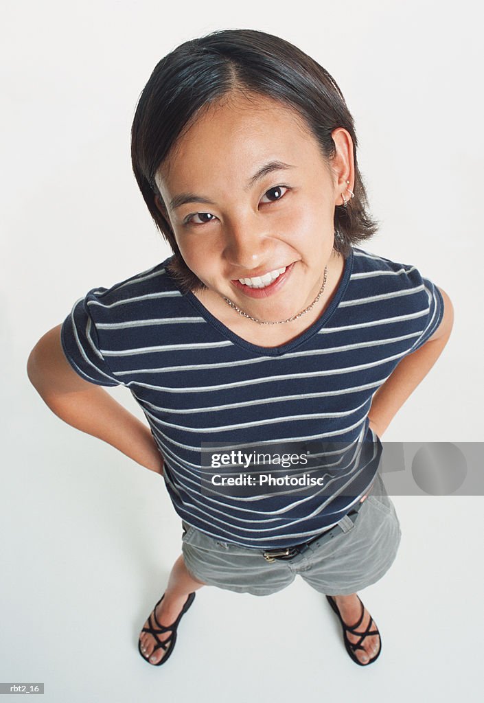 An asian young woman wearing shorts and a striped teeshirt smiles sweetly up at the camera