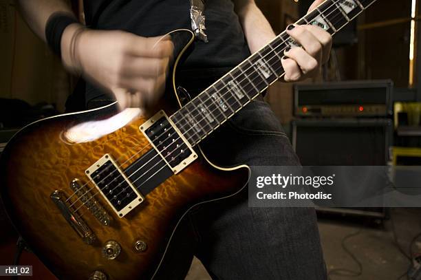 lifestyle portrait of a teenage male as he plays his electric guitar - moderne rockmusik stock-fotos und bilder