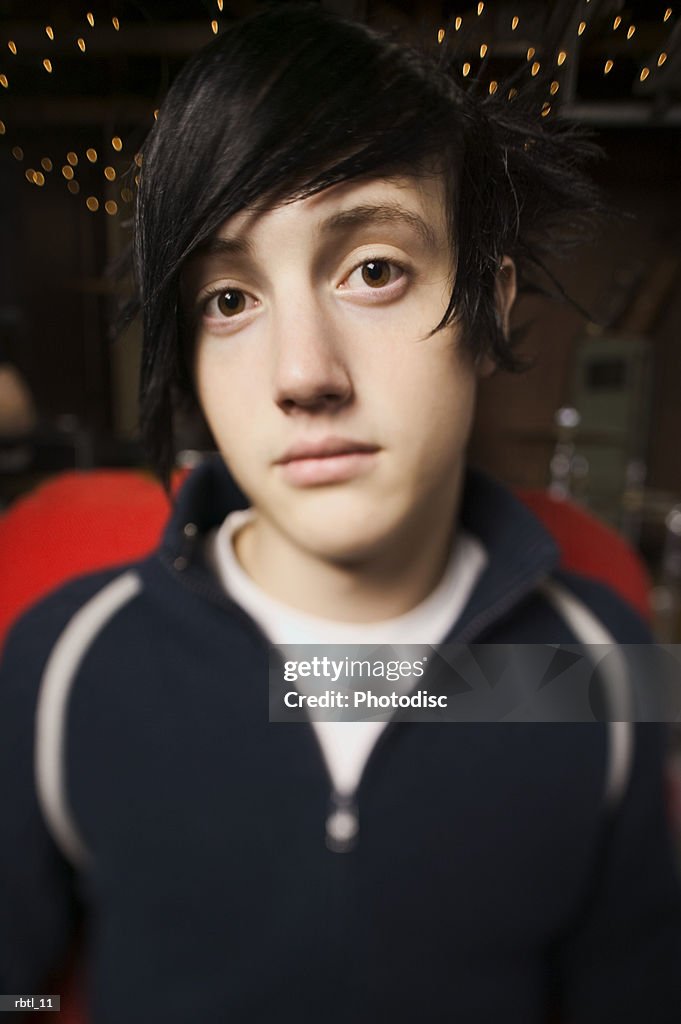 Lifestyle portrait of a teenage male in a black shirt as he sits and looks at the camera