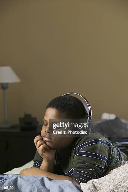lifestyle portrait of a teenage male as he lays on his bed and listens to music through headphones - electronic music 個照片及圖片檔