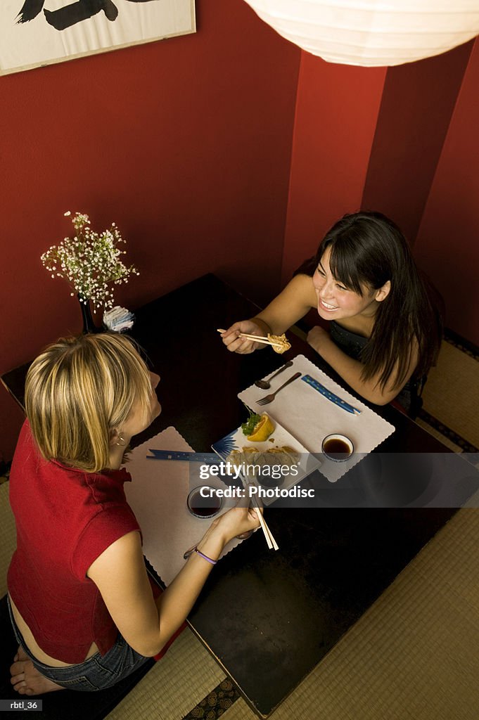 High angle lifestyle portrait of two teenage females as they eat in a booth of a restaurant