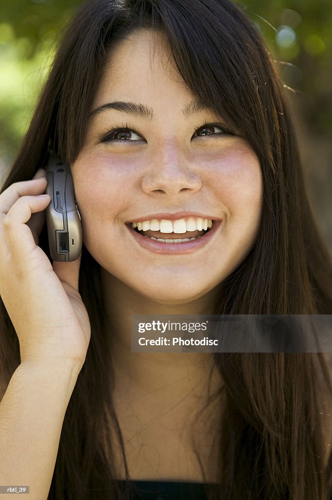 Lifestyle portrait of a teenage female as she talks on a cell phone and smiles brightly