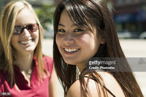 lifestyle portrait of two teenage female friends as they turn and smile at the camera - smile stockfoto's en -beelden