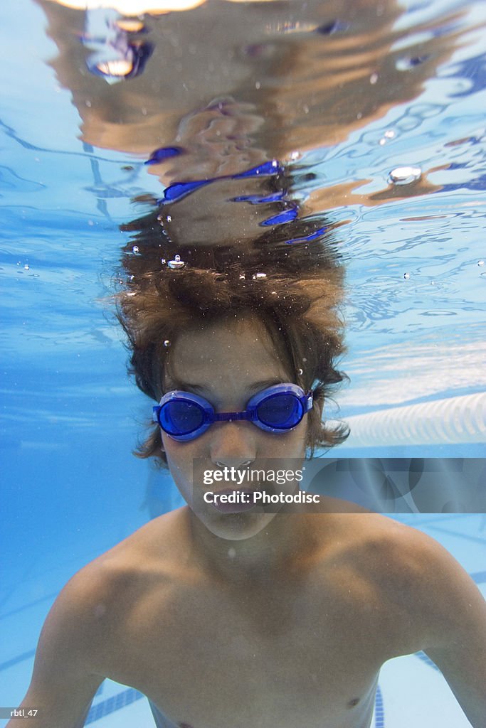 Underwater lifestyle shot of a teenage male in goggles as he swims in a pool