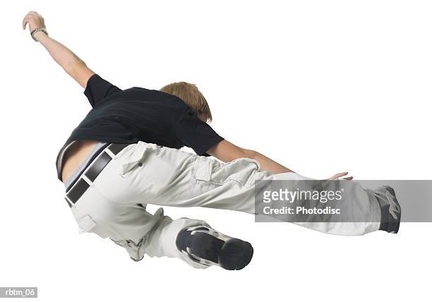 a caucasian male teen in tan pants and a black shirt jumps and kicks through the air - tan tan stock pictures, royalty-free photos & images