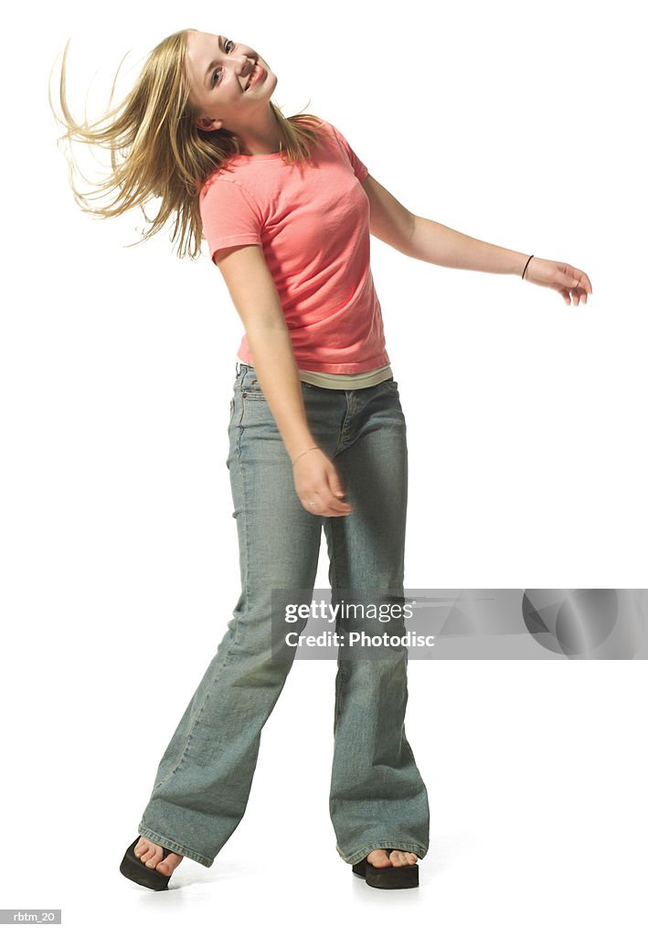 An attractive blonde female teen in jeans and a pink shirt dances playfully