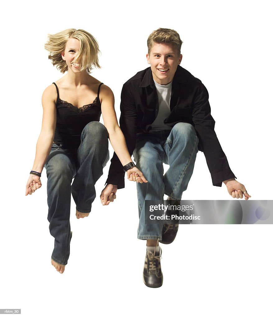 A caucasian couple jump up together and playfully snap their fingers