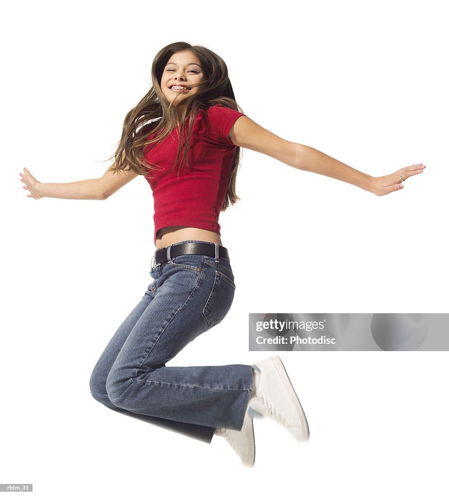 An ethnic teenage female in jeans and a red shirt jumps up playfully