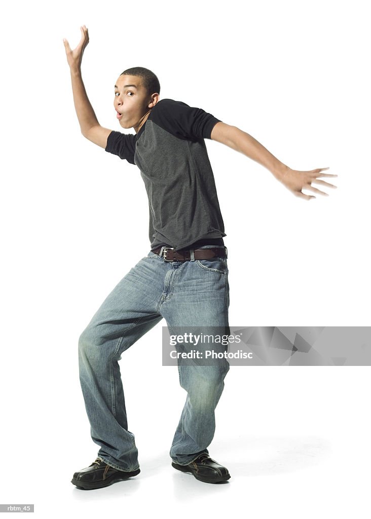 An african american male teen in jeans and a grey shirt does a funny dance