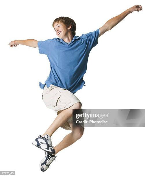 a caucasian male teen in tan shorts and a blue shirt jumps through the air - teen boy shorts stockfoto's en -beelden