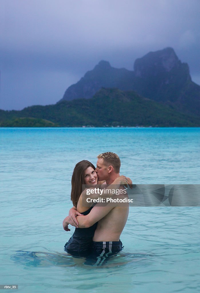 A caucasian couple embrace in the water as they vacation at the beach